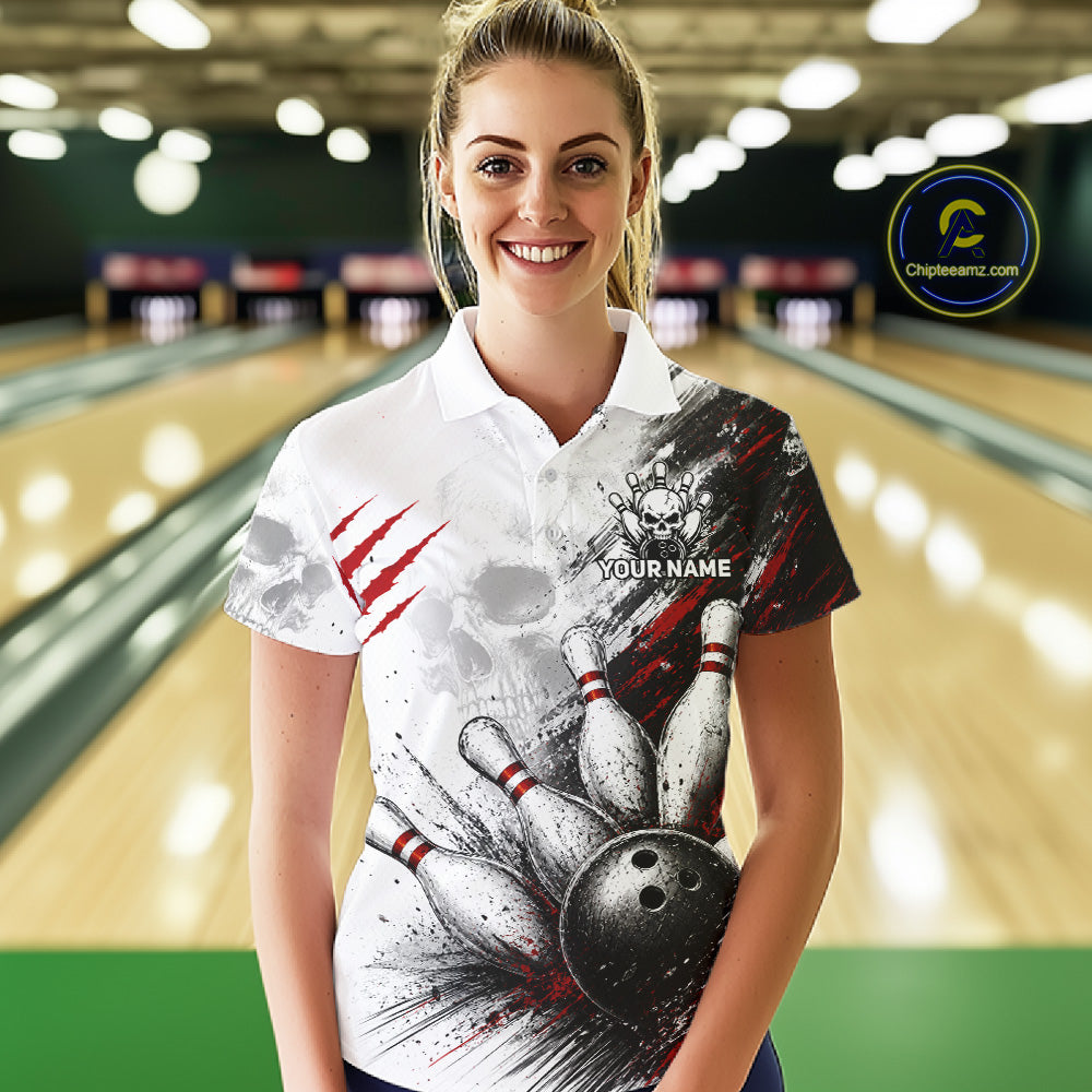 A woman standing in a bowling alley wearing a white short-sleeve polo shirt with a bold bowling-themed graphic print featuring bowling pins, a bowling ball, red claw marks, and a customizable name placeholder on the chest.