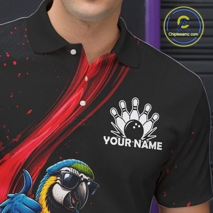 A close-up of a black short-sleeve polo shirt worn by a model, featuring a red abstract graphic on the chest, a white bowling pin and ball graphic with the text 'YOUR NAME', and a colorful parrot illustration in the lower left. A circular 'Chipteeamz.