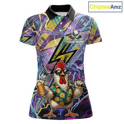A women's short-sleeve polo shirt with a vibrant all-over graphic print. The design features a cartoon rooster wearing sunglasses and a floral shirt, holding a beer mug and a bat, set against a background of purple and yellow lightning bolts and geometric patterns.
