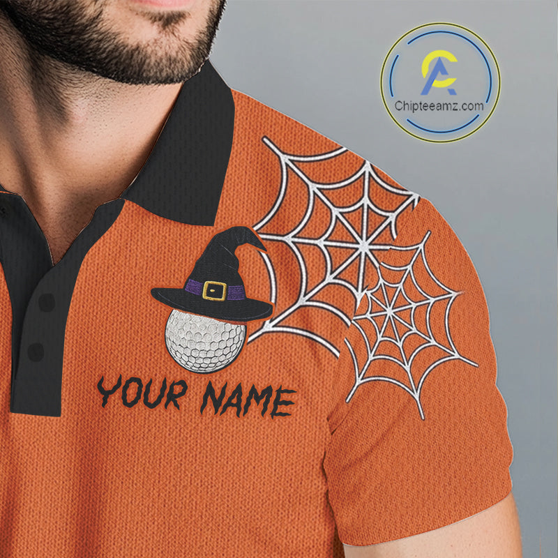 Close-up of a man wearing an orange polo shirt with a black collar. The shirt features a white spiderweb graphic on the right shoulder and a customizable patch on the left chest with a black witch hat, a white golf ball, and the text 'YOUR NAME'.