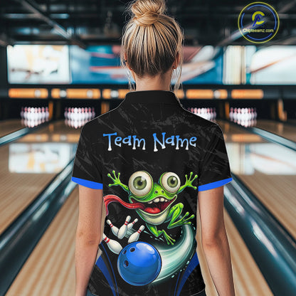 A woman viewed from behind wearing a black bowling-themed short-sleeve shirt with a colorful cartoon frog graphic and the text 'Team Name' on the back. The background shows a blurred bowling alley with lanes and pins.