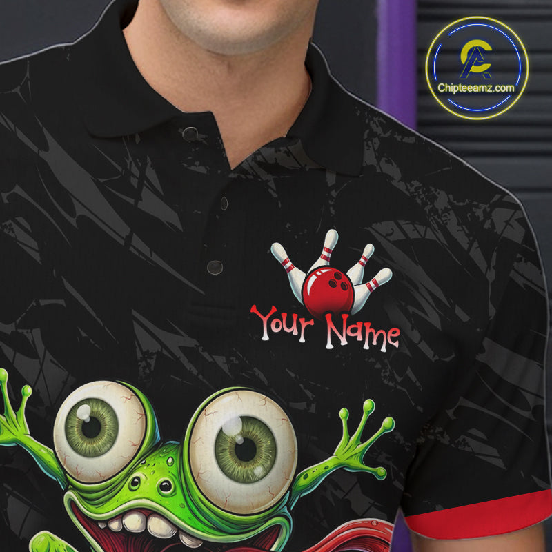 A close-up of a man wearing a black short-sleeve polo shirt with a bowling-themed graphic. The shirt features a green cartoon frog with large eyes and a red bowling ball and pins design above the text 'Your Name' with a placeholder name.