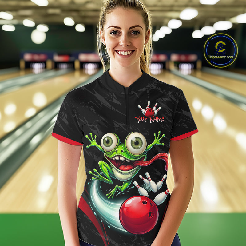 A woman stands in a bowling alley wearing a black short-sleeve bowling shirt with a large green cartoon frog graphic, a red bowling ball, and 'Your Name' text on the chest. A circular 'Chipteeamz"
