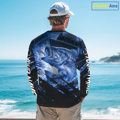 Person wearing a long sleeve fishing shirt with a blue largemouth bass fish design, standing by the ocean.