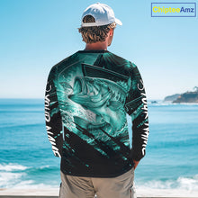 Load image into Gallery viewer, Person wearing a teal and black bass fishing shirt with a fish design, standing by the ocean.