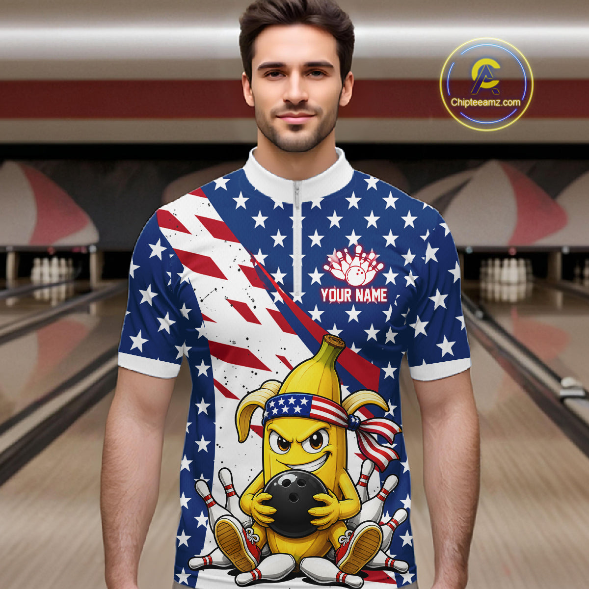 Man wearing a patriotic-themed quarter zip shirt with a banana cartoon character holding a bowling ball in a bowling alley.