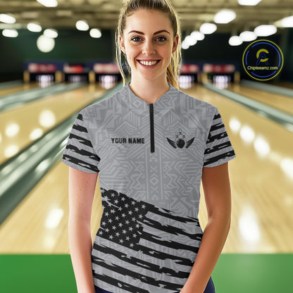 Front view of woman wearing a grey American flag bowling polo shirt inside a bowling alley.