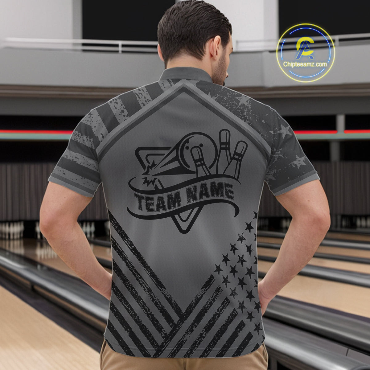 Back view of man wearing a grey American flag bowling quarter zip shirt in a bowling alley.