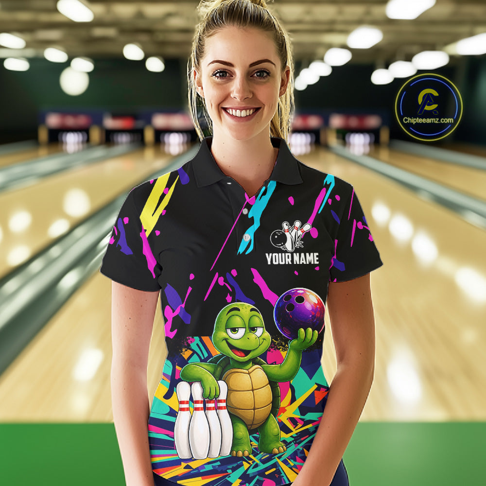 Woman wearing a colorful bowling-themed shirt with a turtle graphic in a bowling alley.