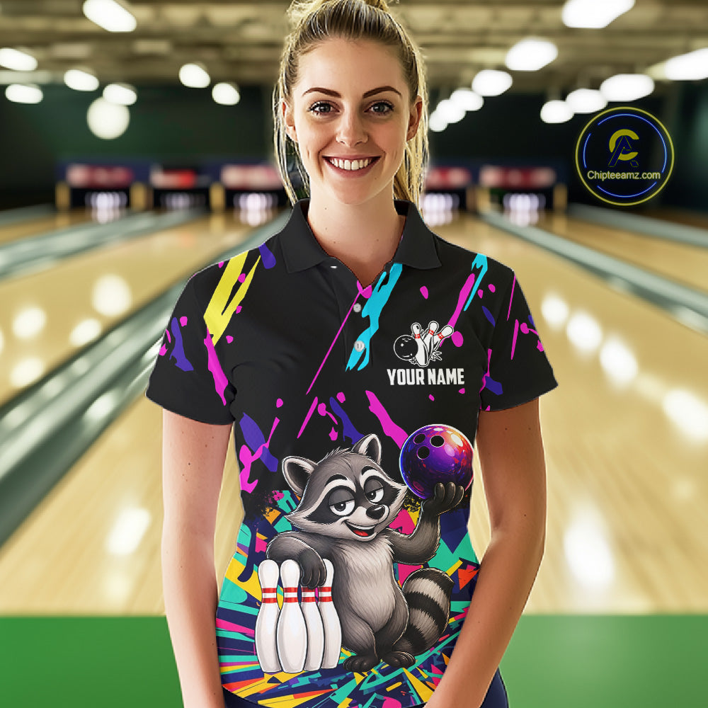 Woman wearing a colorful bowling-themed shirt with a raccoon graphic in a bowling alley.