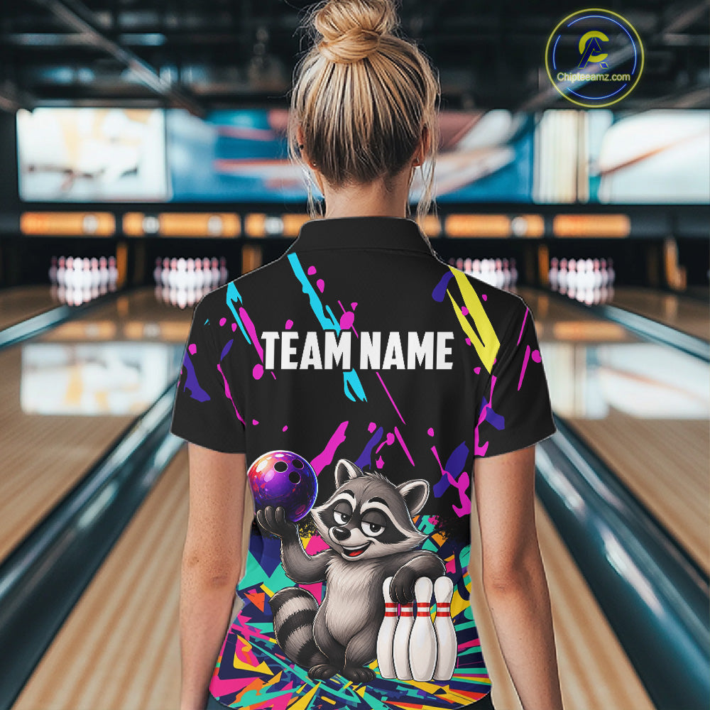 Person wearing a colorful bowling-themed shirt with a raccoon design in a bowling alley.