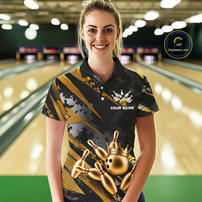 Woman wearing a black and gold bowling shirt with a crown design on a bowling alley.