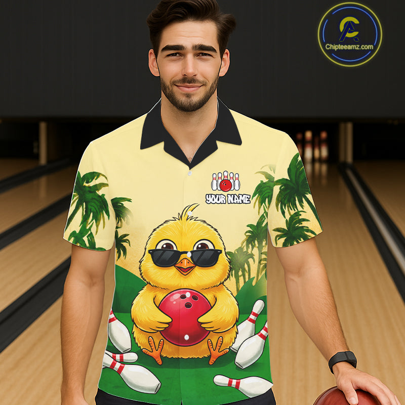 Man wearing a yellow polo shirt with a cartoon chick design in a bowling alley.