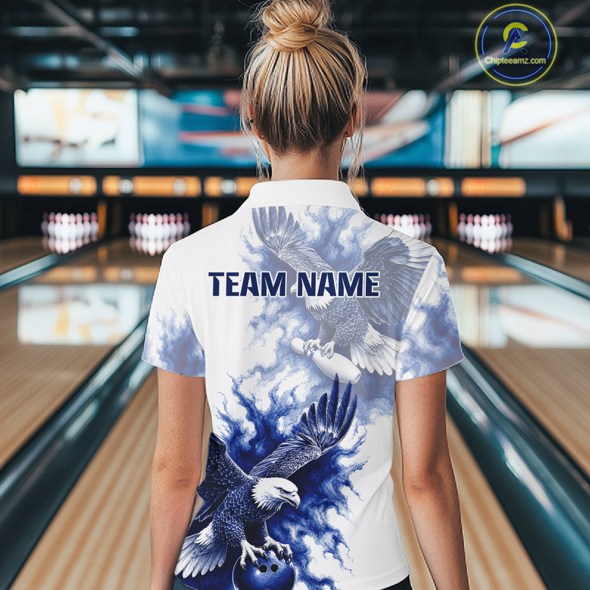 Female bowler wearing Blue & White Eagle bowling jersey in bowling alley, eagle symbolizes freedom, courage, victory, American heritage, personalized tournament apparel.